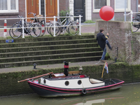 906666 Afbeelding van een jongeman die een ballon gaat ophangen op de kade bij de Bemuurde Weerd W.Z. te Utrecht, in ...